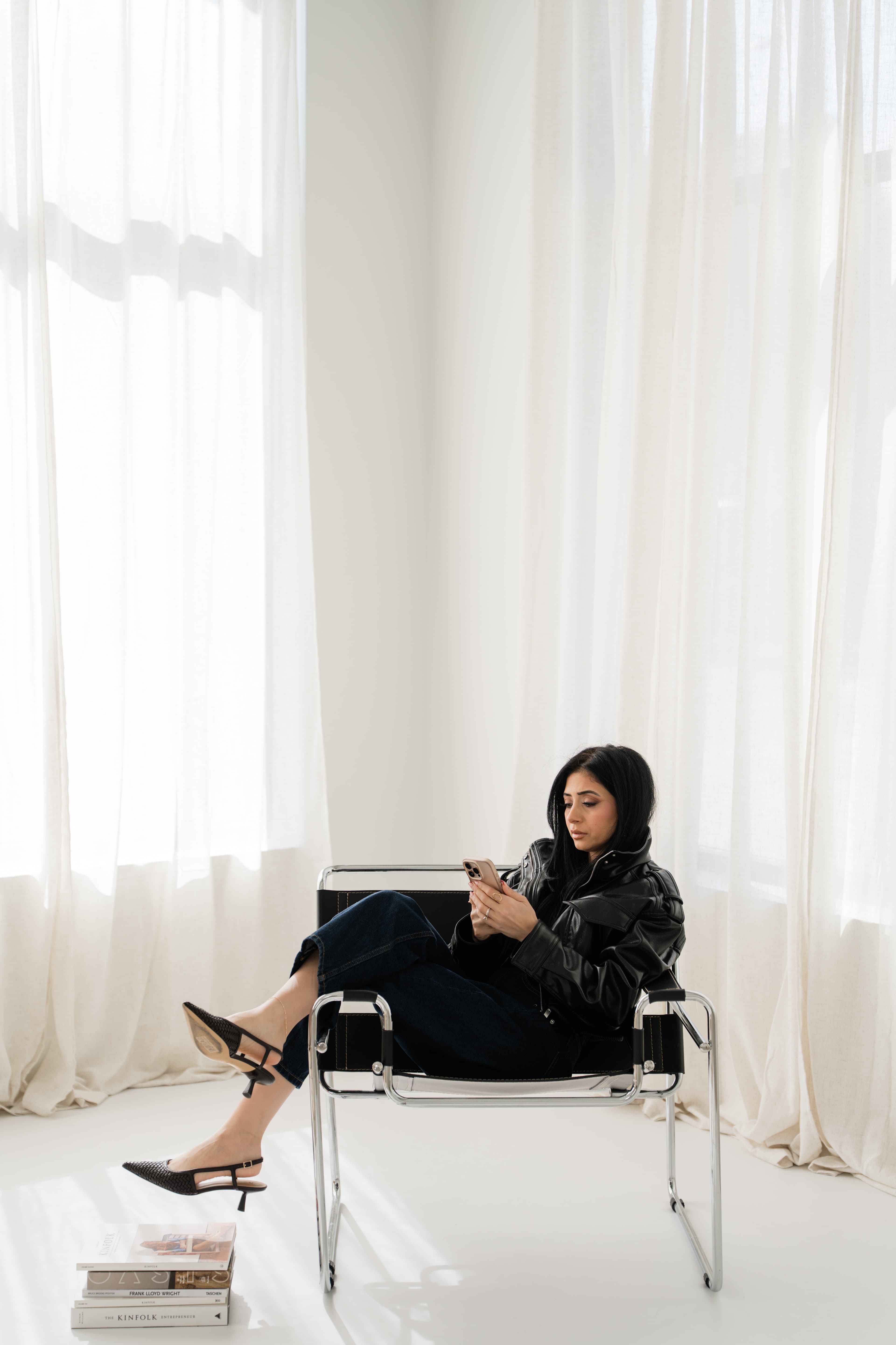Jumana seated in a studio chair using her phone